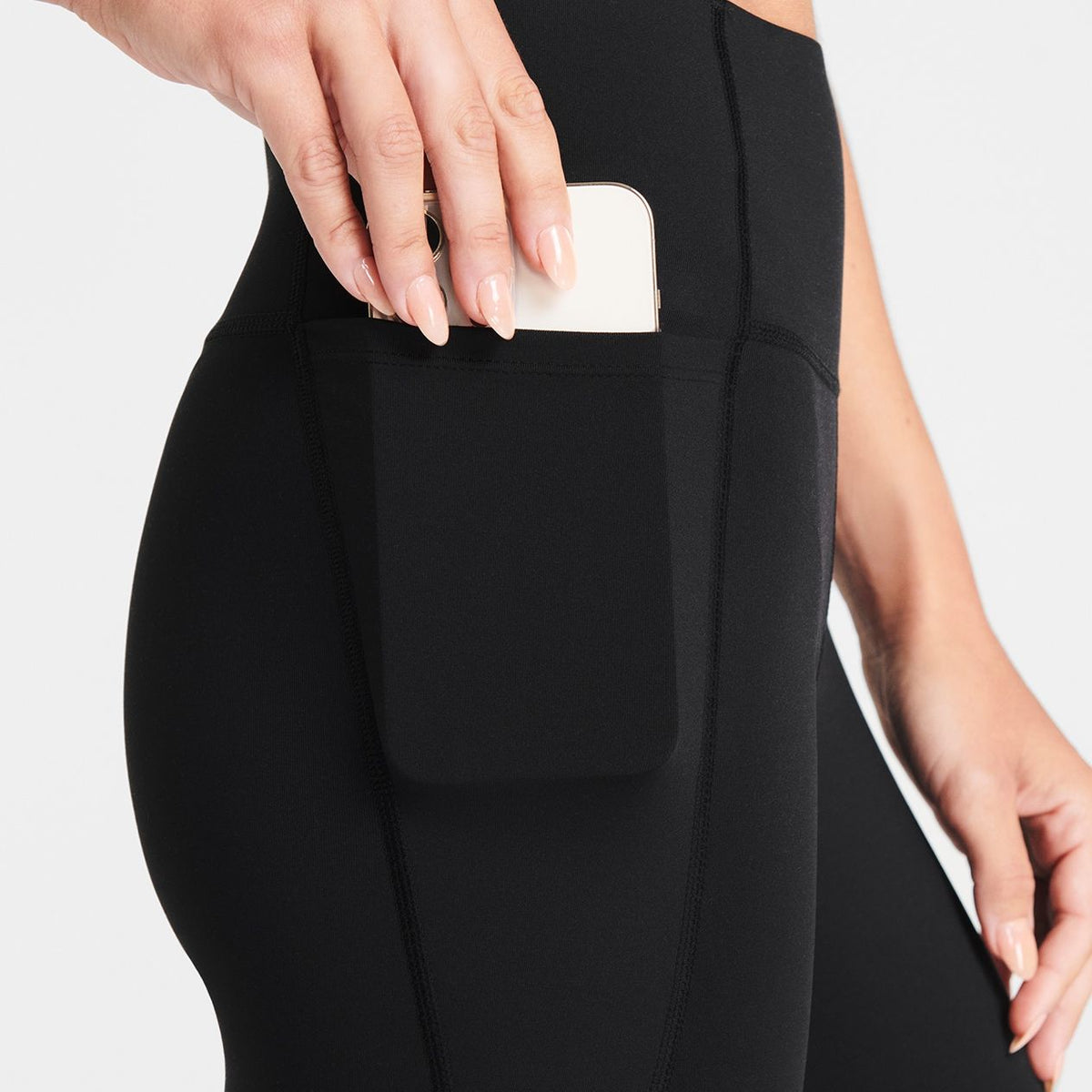 Woman wearing black Trimline Natural-Waist 7/8 Leggings by Definite Articles. Closeup of pocket.