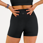 Woman wearing black Trimline 5" Shorts by Definite Articles.