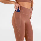 Woman wearing carob brown Trimline 7/8 Leggings by Definite Articles. Closeup on pocket.