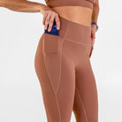 Woman wearing carob brown Trimline Natural-Waist 7/8 Leggings by Definite Articles. Closeup on pocket.
