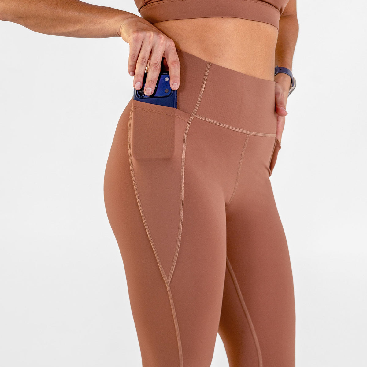 Woman wearing carob brown Trimline Natural-Waist 7/8 Leggings by Definite Articles. Closeup on pocket.